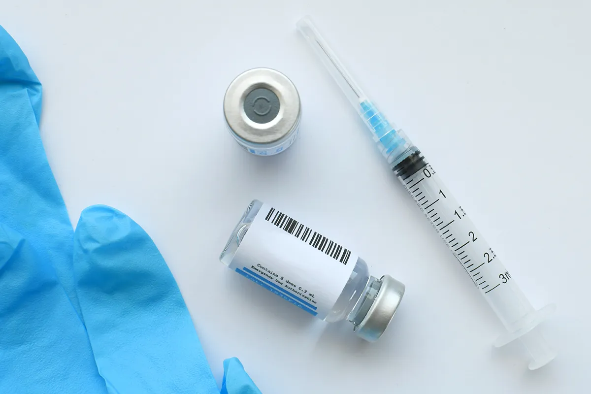 Medizin in Ampullen und eine Spritze auf einer Oberfläche liegend/stehend