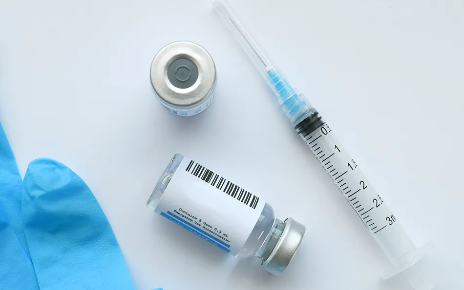 Medizin in Ampullen und eine Spritze auf einer Oberfläche liegend/stehend