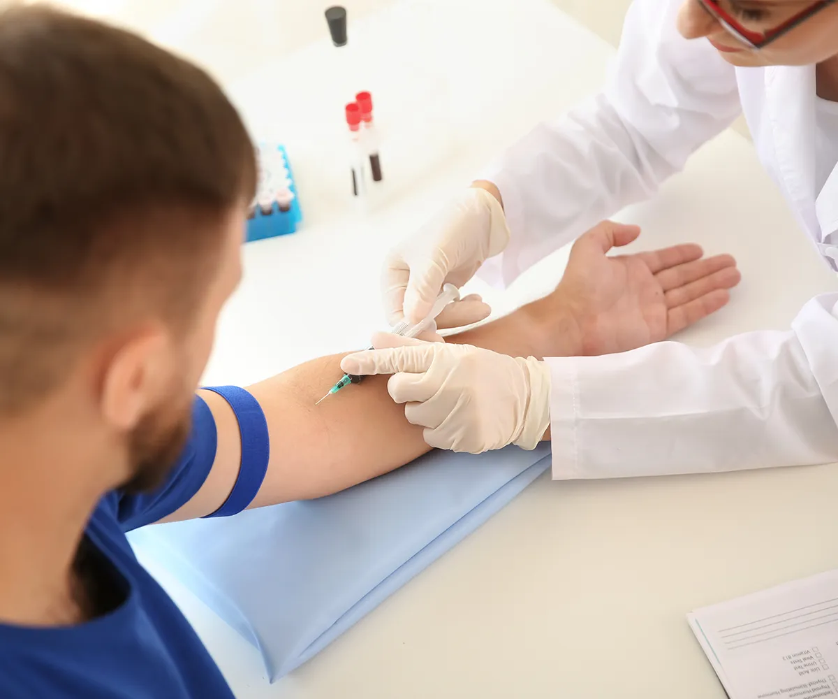 Schmerzhaften Behandlungen Spritzen Eine weibliche medizinische Fachkraft nimmt bei einer männlichen Person am linken Arm Blut ab