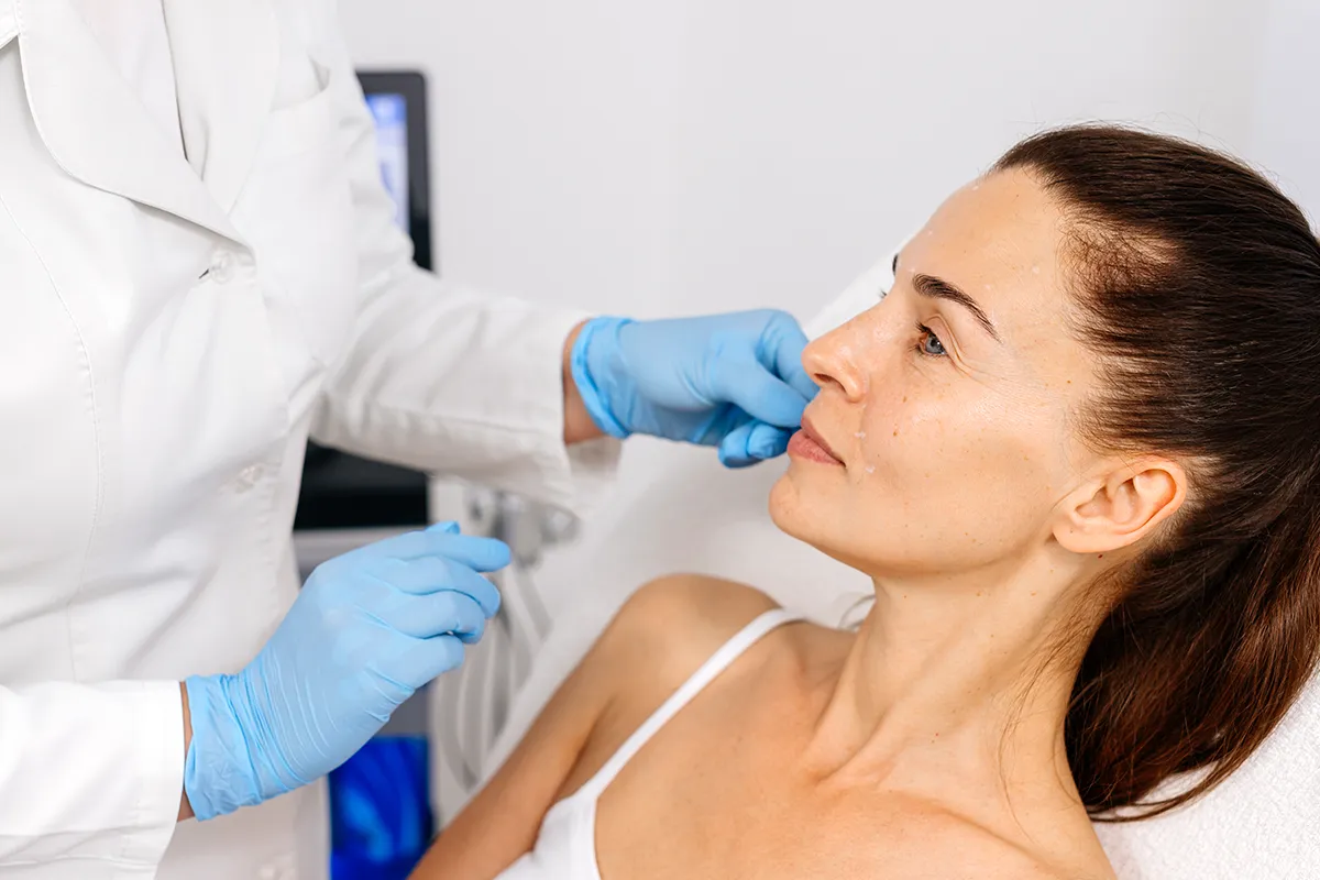 Abstimmung mit Behandler vor Creme Anwendung Medizinisches Personal steh vor einer liegenden älter wirkenden weiblichen Person