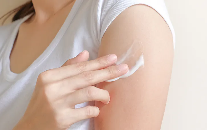 Creme unter Fingern auf einem Oberarm einer weiblichen Person