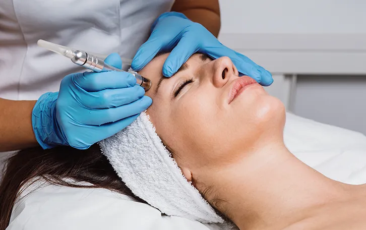 Ein medizinisches Personal setzt eine Spritze auf der Stirn einer liegenden Person an